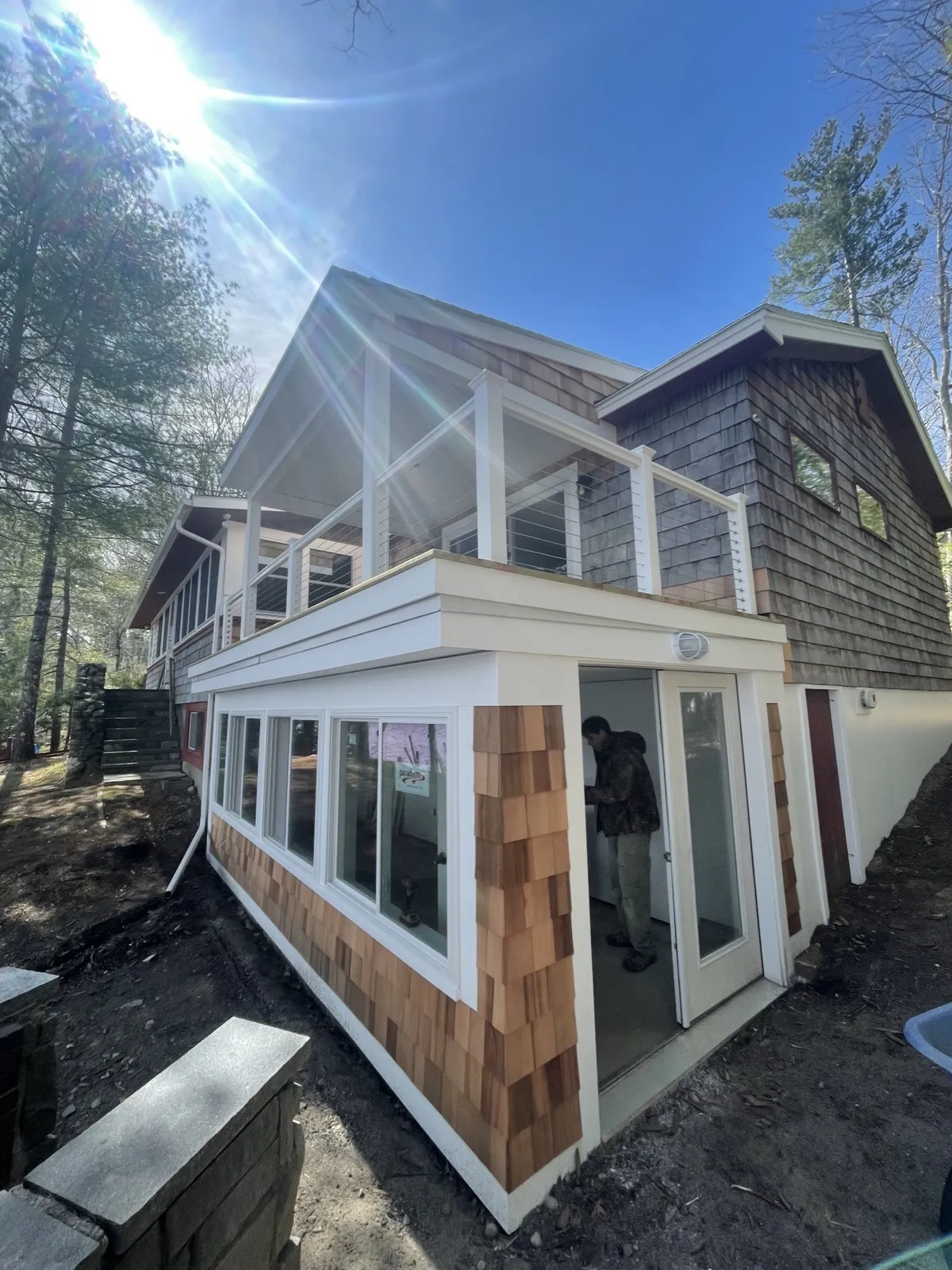 Covered deck with a 4-season porch below at a lake home in Lyman, Maine